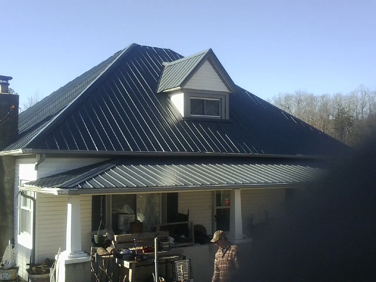Dark blue standing seam metal roof with a dormer above a front porch in Gracewood