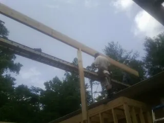 Carpenter setting a ridge beam over a new addition frame — Ice Dam Removal by Roofing Brothers in Gracewood