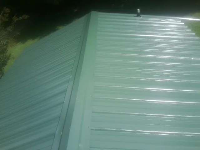 New green metal panels meeting at the ridge of a roof — Flat Roof Repair work by our crew in Gracewood