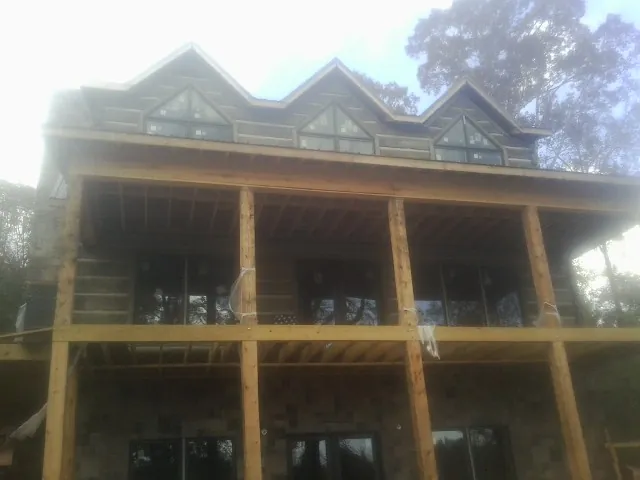 Dormers and porch framing on a large log home under construction — Roof Coating work by our crew in Gracewood