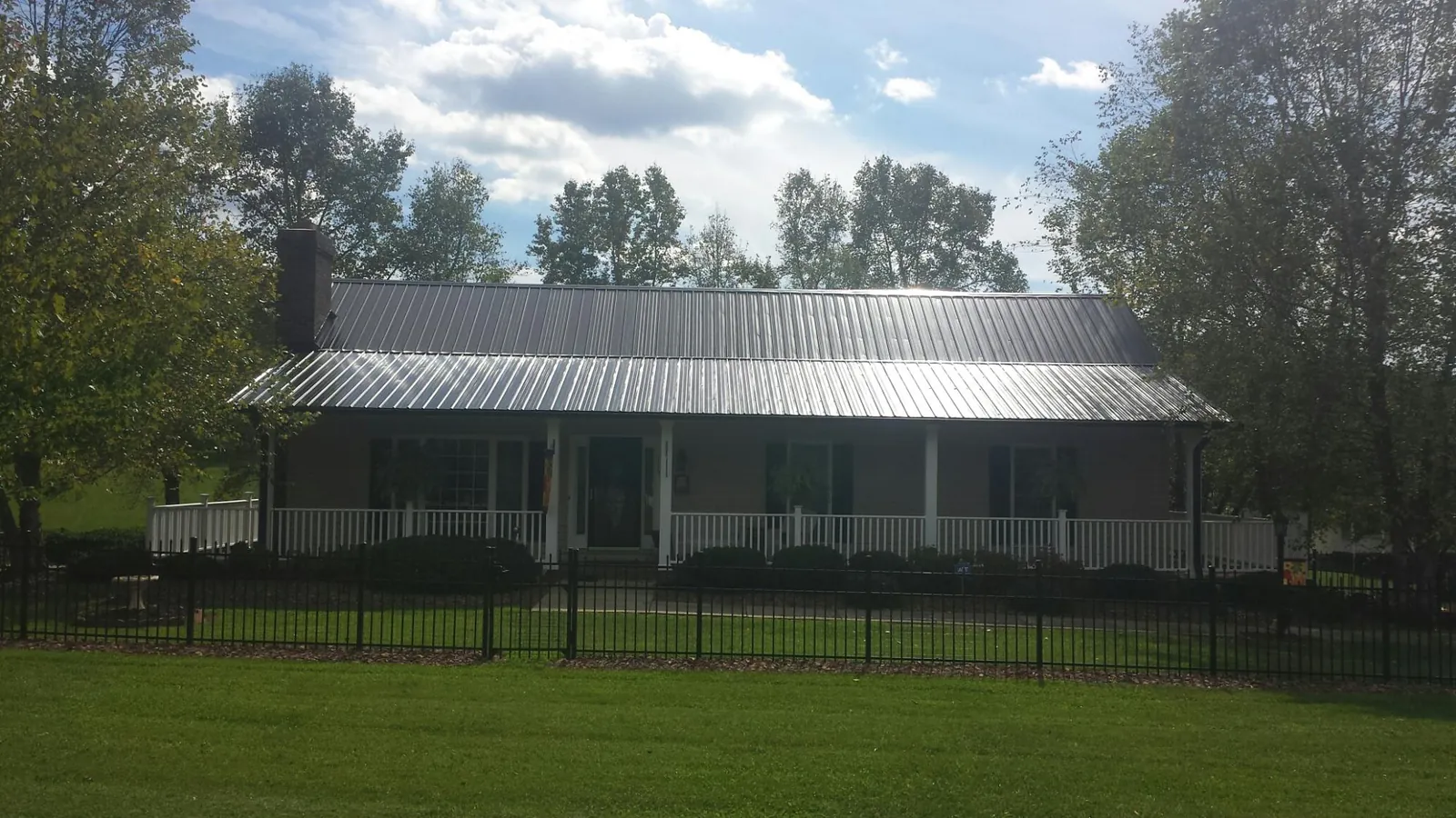 Gray metal roof on a brick ranch with a full width front porch — Gutter Guard Installation work by our crew in Gracewood