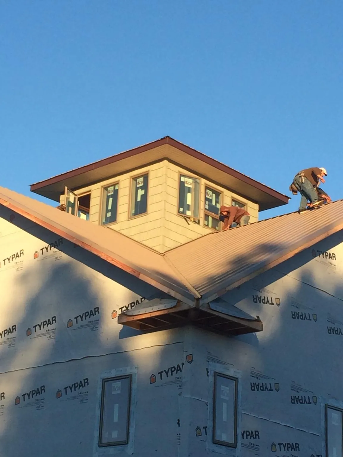 Roofers working around a rooftop cupola on a new metal roof at sunset — Roof Waterproofing in Gracewood by Roofing Brothers